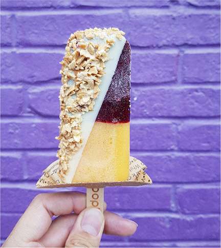 ice cream bar dipped in peanuts being held up in front of a blue